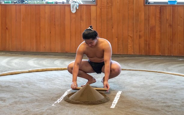 Sumo wrestler preparing practice ring at a sumo stable in Japan.