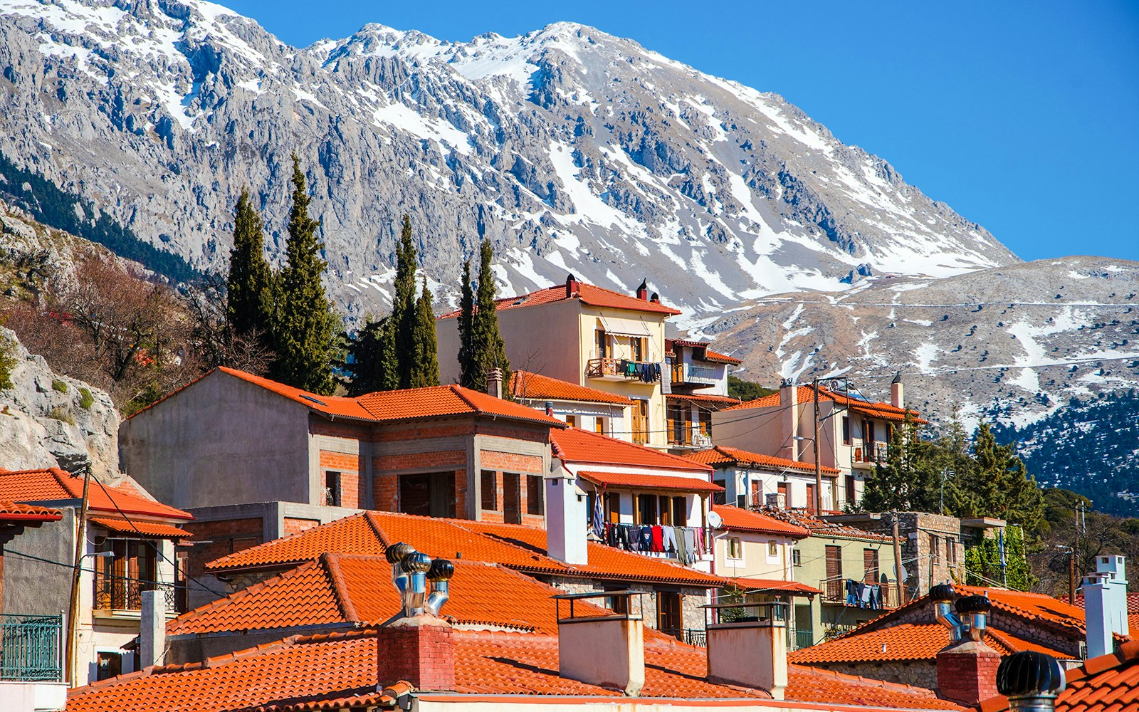 Arachova Village with red-roofed houses and snow-capped mountains in the background.