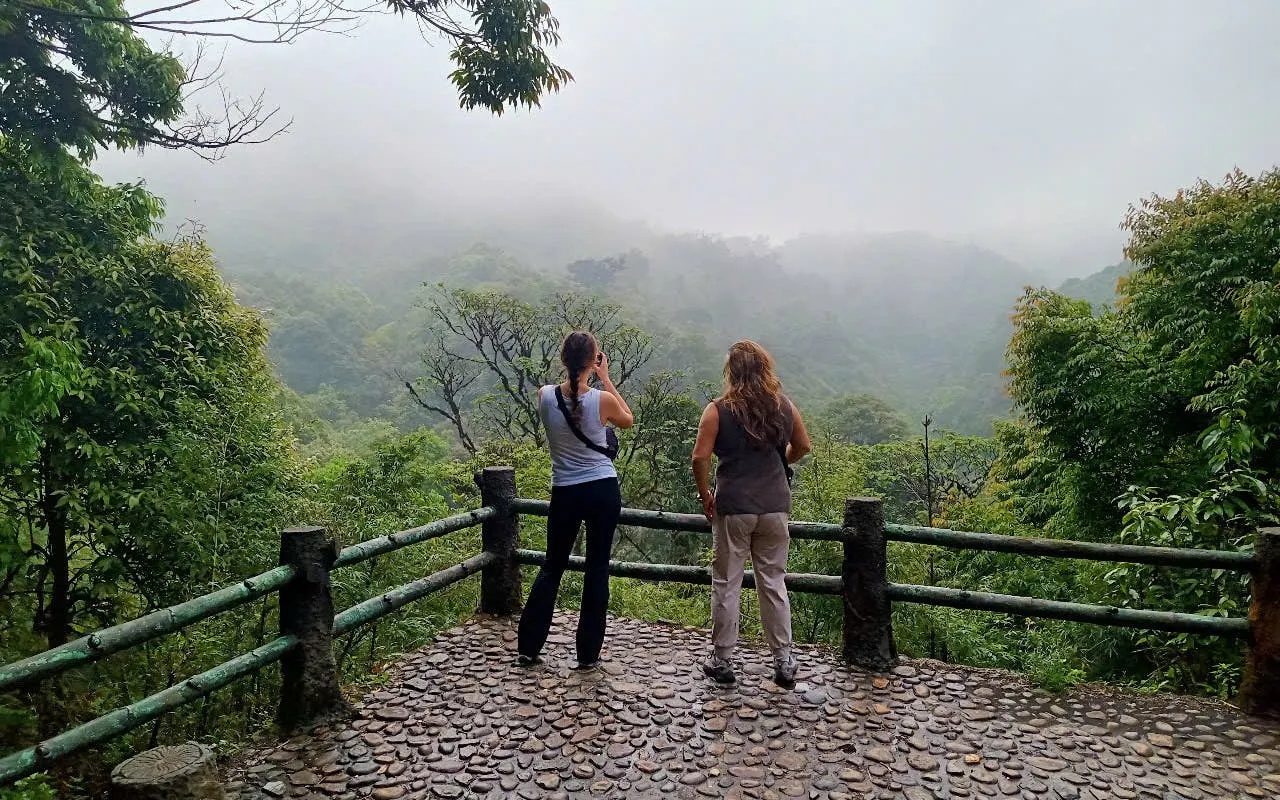 Two people on a viewpoint overlooking misty green hills in Sapa, Vietnam.