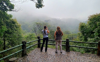 Two people on a viewpoint overlooking misty green hills in Sapa, Vietnam.