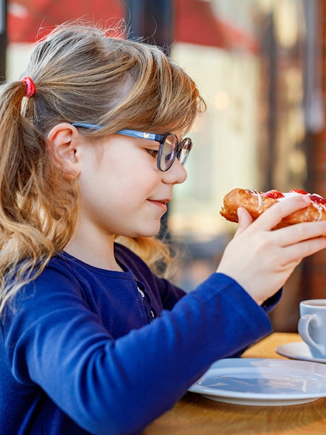 Child enjoying pastry at Brasserie Rosalie breakfast table.