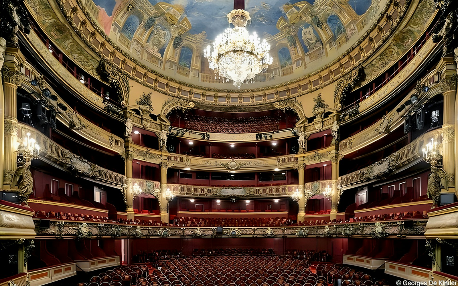 Interior view of Teatro Colon with ornate balconies and grand chandelier.