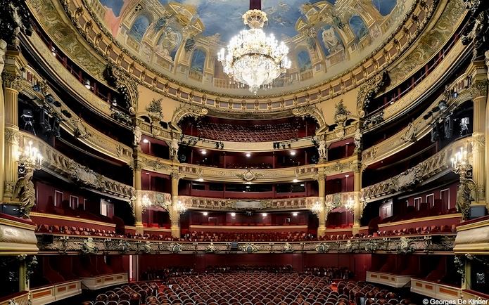 Interior view of Teatro Colon with ornate balconies and grand chandelier.