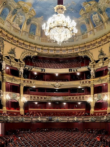 Interior view of Teatro Colon with ornate balconies and grand chandelier.