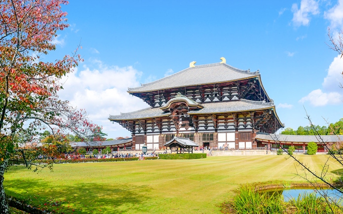 Tōdai-ji Temple in Nara, Japan with autumn foliage and a clear blue sky.