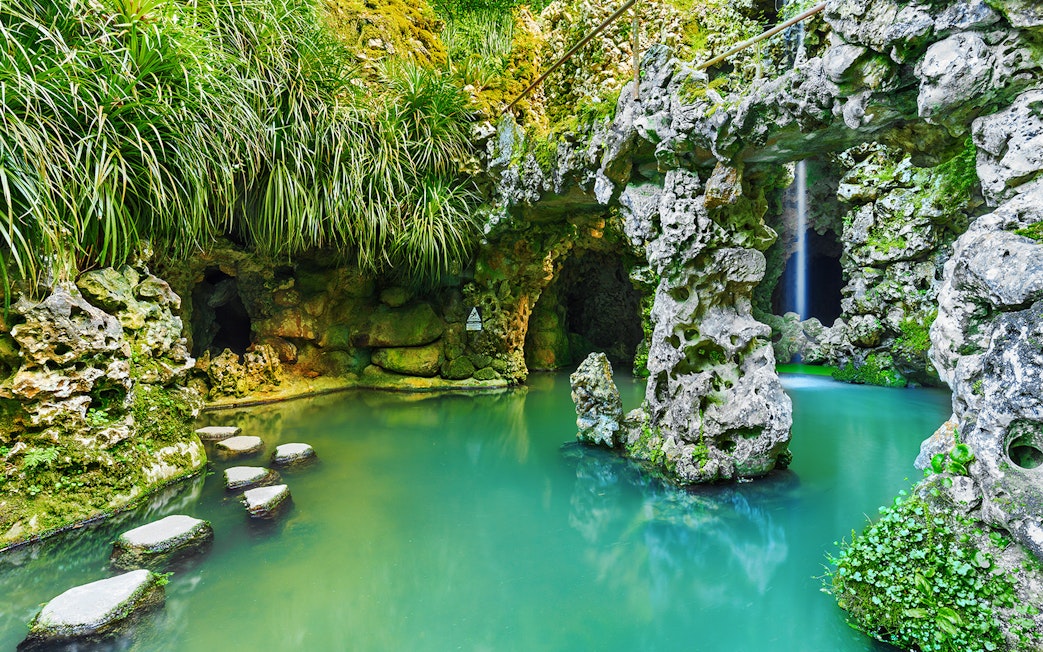 Stone pathway over turquoise water in Quinta da Regaleira garden, Sintra, Portugal.