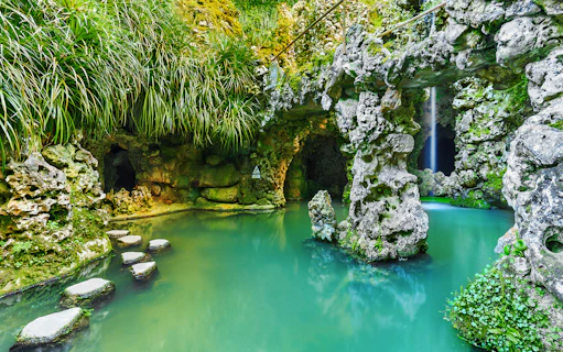 Stone pathway over turquoise water in Quinta da Regaleira garden, Sintra, Portugal.