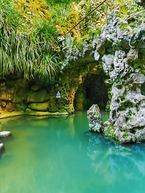 Stone pathway over turquoise water in Quinta da Regaleira garden, Sintra, Portugal.