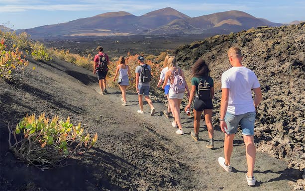 Group hiking on volcanic terrain at Timanfaya National Park, Lanzarote.
