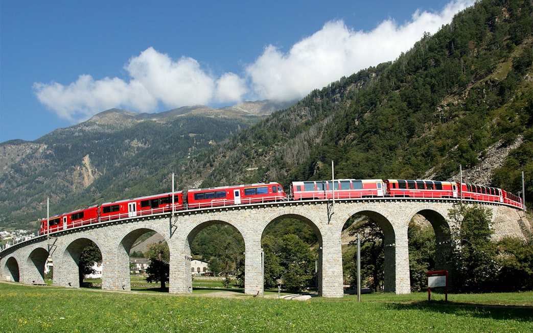 Bernina Express crossing a stone viaduct in the Swiss Alps.