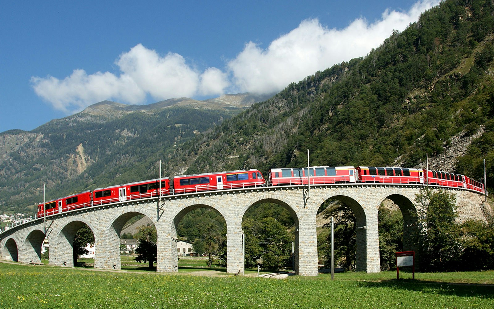 Bernina Express crossing a stone viaduct in the Swiss Alps.