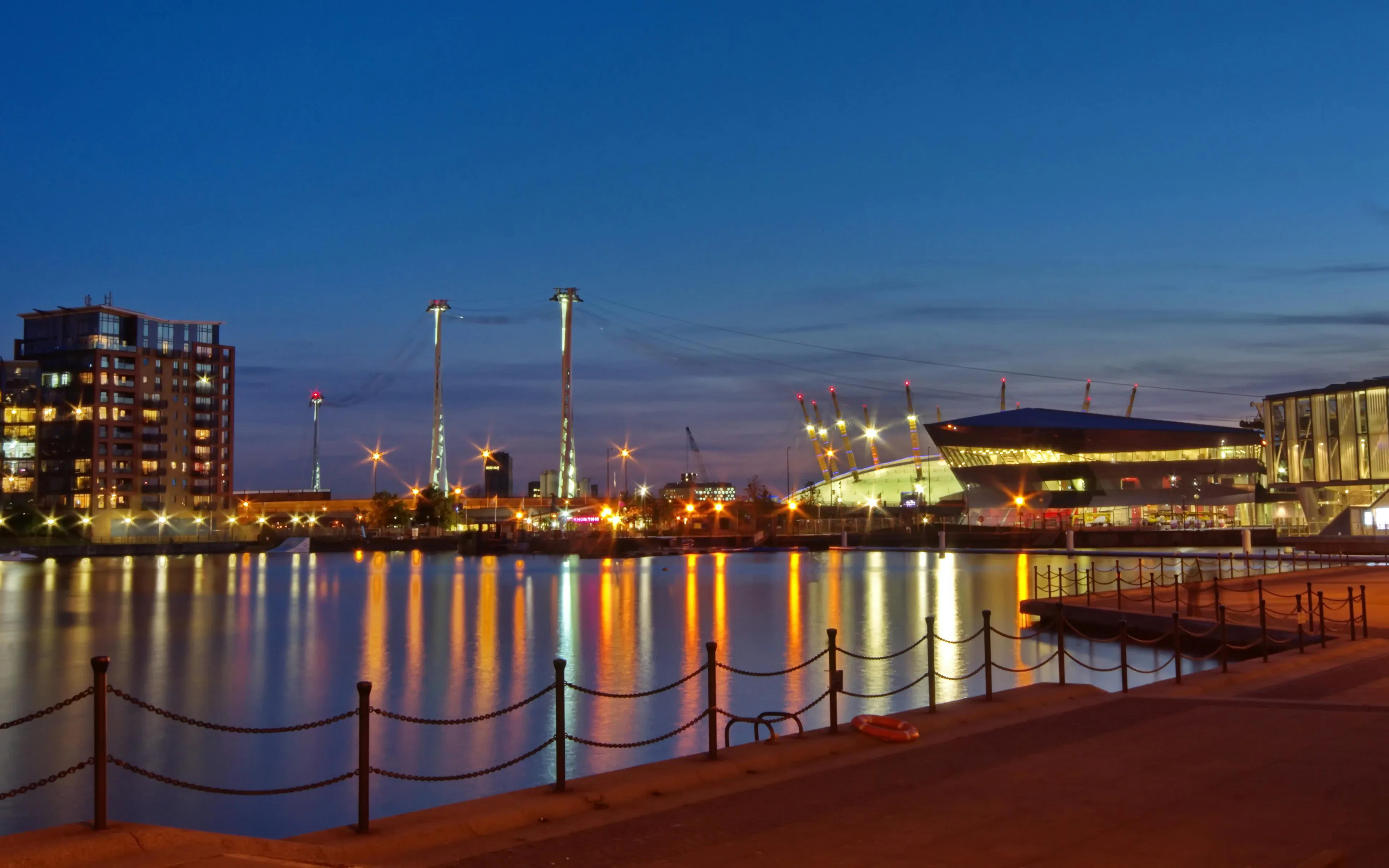 Emirates Air Line cable cars over River Thames at night, London skyline in view.