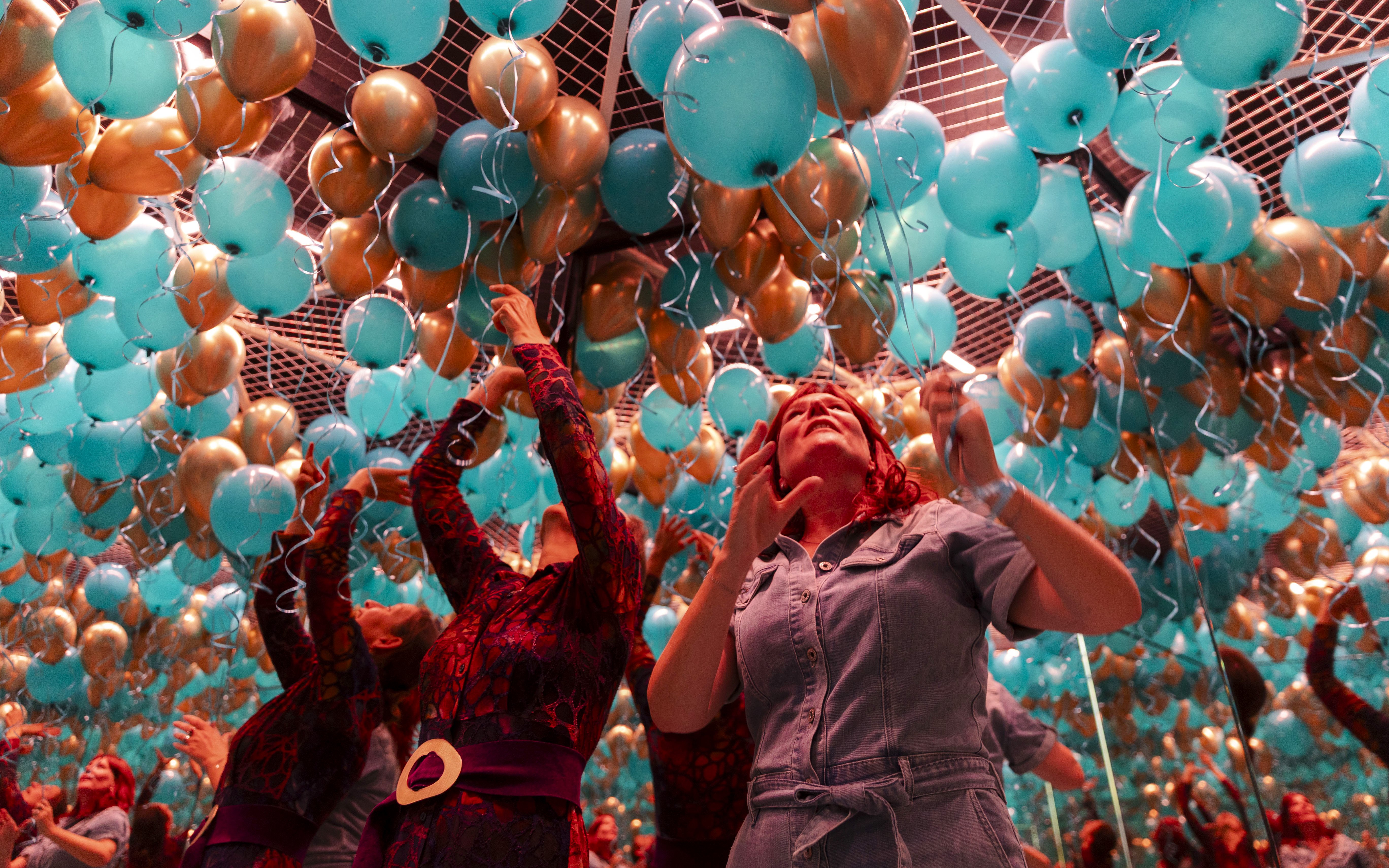 Guests interacting with teal and gold balloons at Museum of Illusions Amsterdam.
