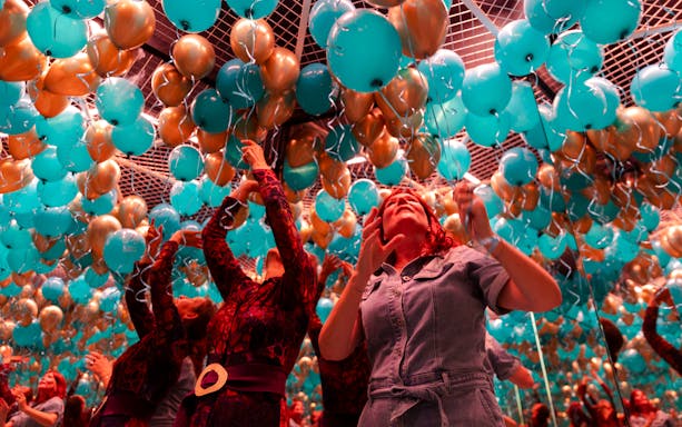 Guests interacting with teal and gold balloons at Museum of Illusions Amsterdam.