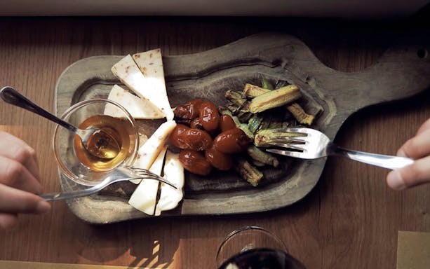 Cheese, tomatoes, and zucchini on a wooden platter during a Tuscan wine tour tasting.