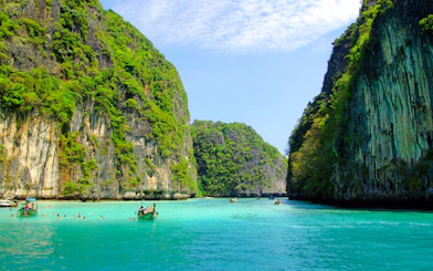 Tourists swimming and boating in turquoise waters surrounded by limestone cliffs, Krabi.