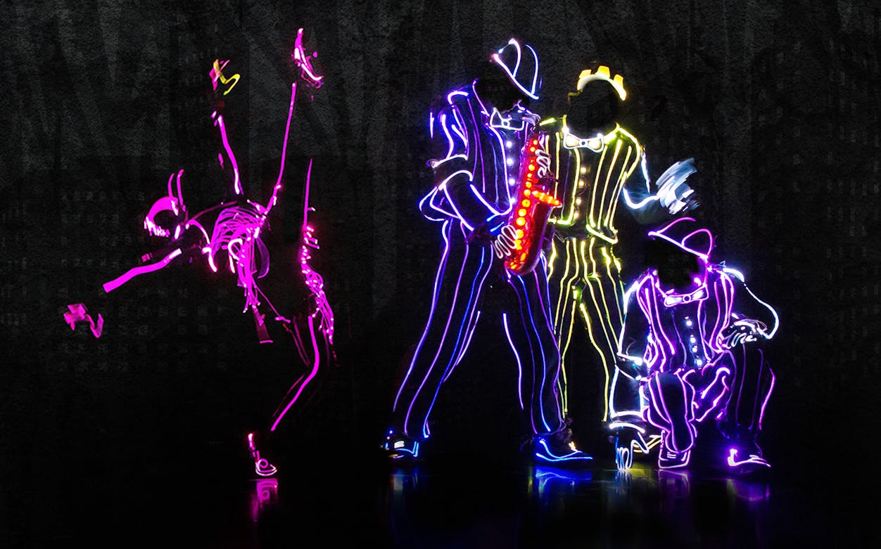 Dancers in neon light suits performing at iLuminate show.