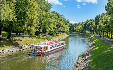Stockholm hop-on hop-off boat cruising along a tree-lined canal.