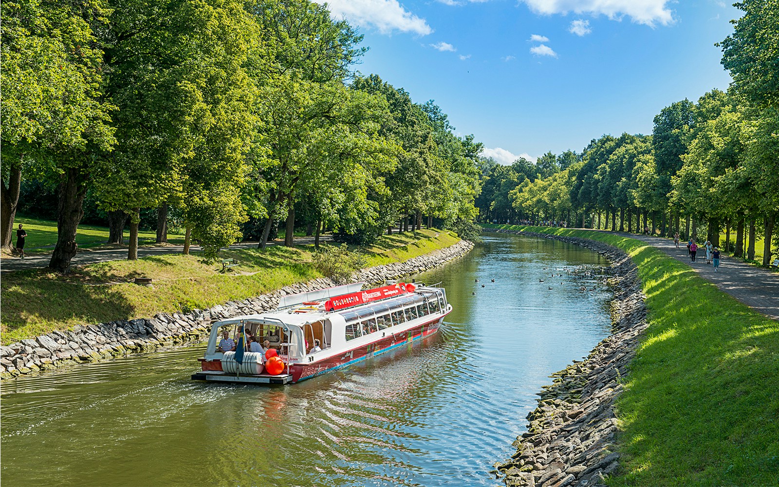 Tourists enjoying a Stockholm boat HOHO tour on a sunny day with scenic city views