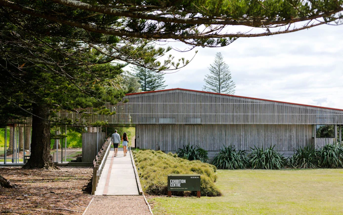 Visitors walking towards Rotoroa Island Exhibition Centre surrounded by trees.