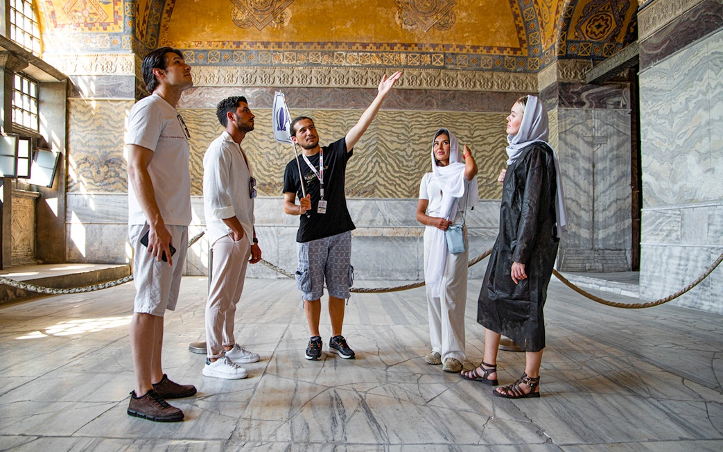Tour group with guide inside Hagia Sophia, Istanbul, discussing historical details.