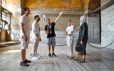 Tour group with guide inside Hagia Sophia, Istanbul, discussing historical details.
