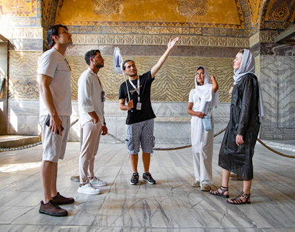 Tour group with guide inside Hagia Sophia, Istanbul, discussing historical details.