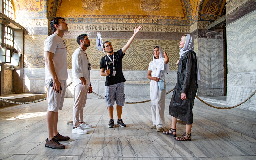 Tour group with guide inside Hagia Sophia, Istanbul, discussing historical details.