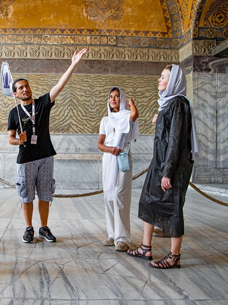 Tour group with guide inside Hagia Sophia, Istanbul, discussing historical details.