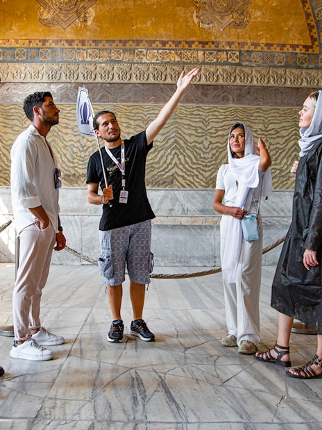Tour group with guide inside Hagia Sophia, Istanbul, discussing historical details.