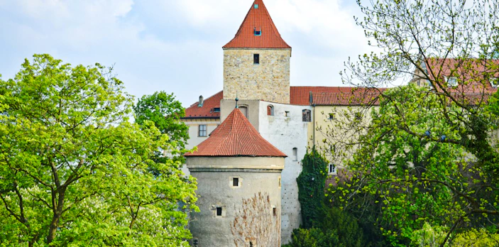 Daliborka Tower at Prague Castle surrounded by lush greenery.