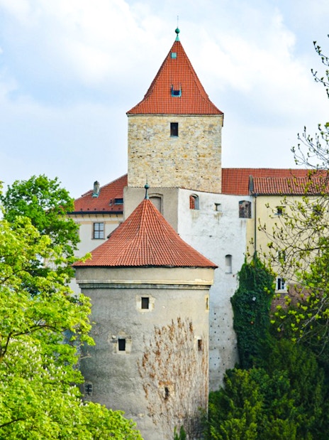Daliborka Tower at Prague Castle surrounded by lush greenery.