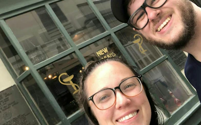 Visitors smiling outside a historic building in the New Orleans French Quarter.