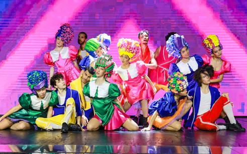 Performers in colorful costumes on stage during Paris: My First Cabaret show.