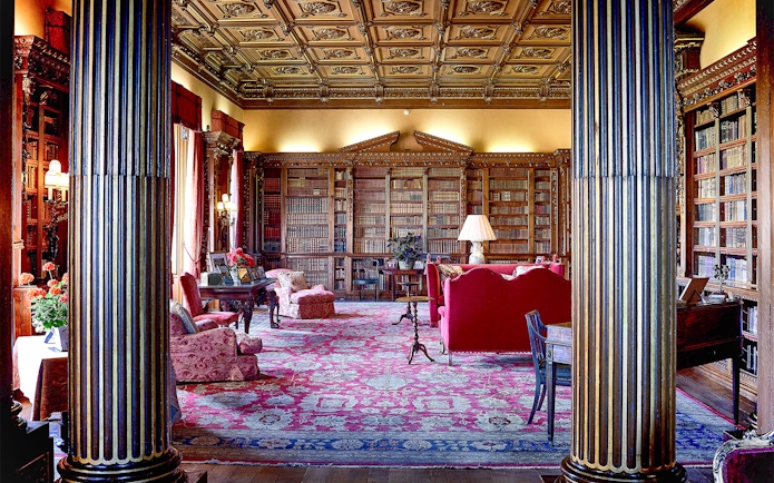 Highclere Castle library with ornate ceiling, bookshelves, and red furnishings.