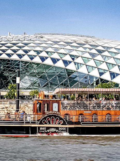 Cruise boat on the Danube River in Budapest with modern glass building in background.