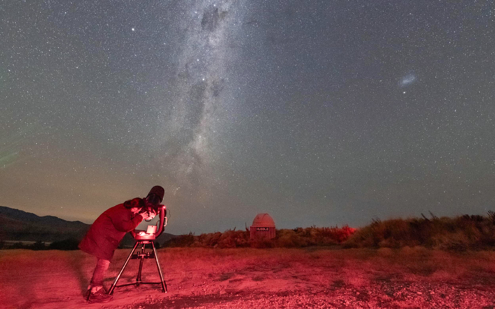 Person setting up a telescope under a starry sky at The Crater Stargazing Experience.