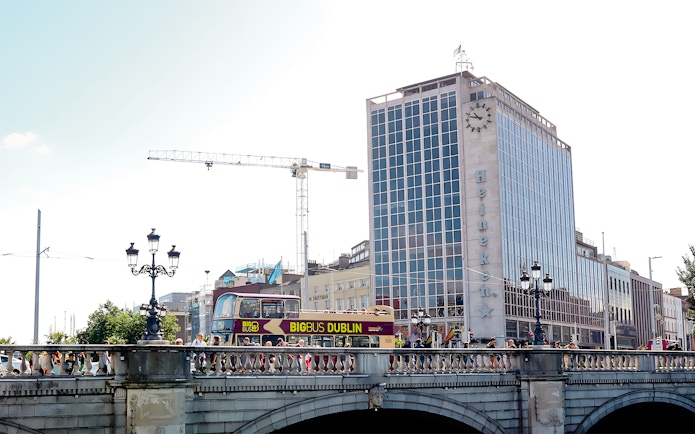 Big Bus Dublin crossing bridge with Heineken building in background.