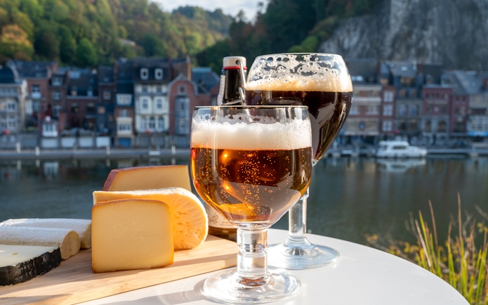 Belgian abbey beer and cheeses by a riverside in Dinant, Belgium.