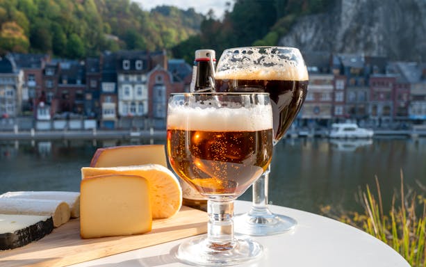 Belgian abbey beer and cheeses by a riverside in Dinant, Belgium.