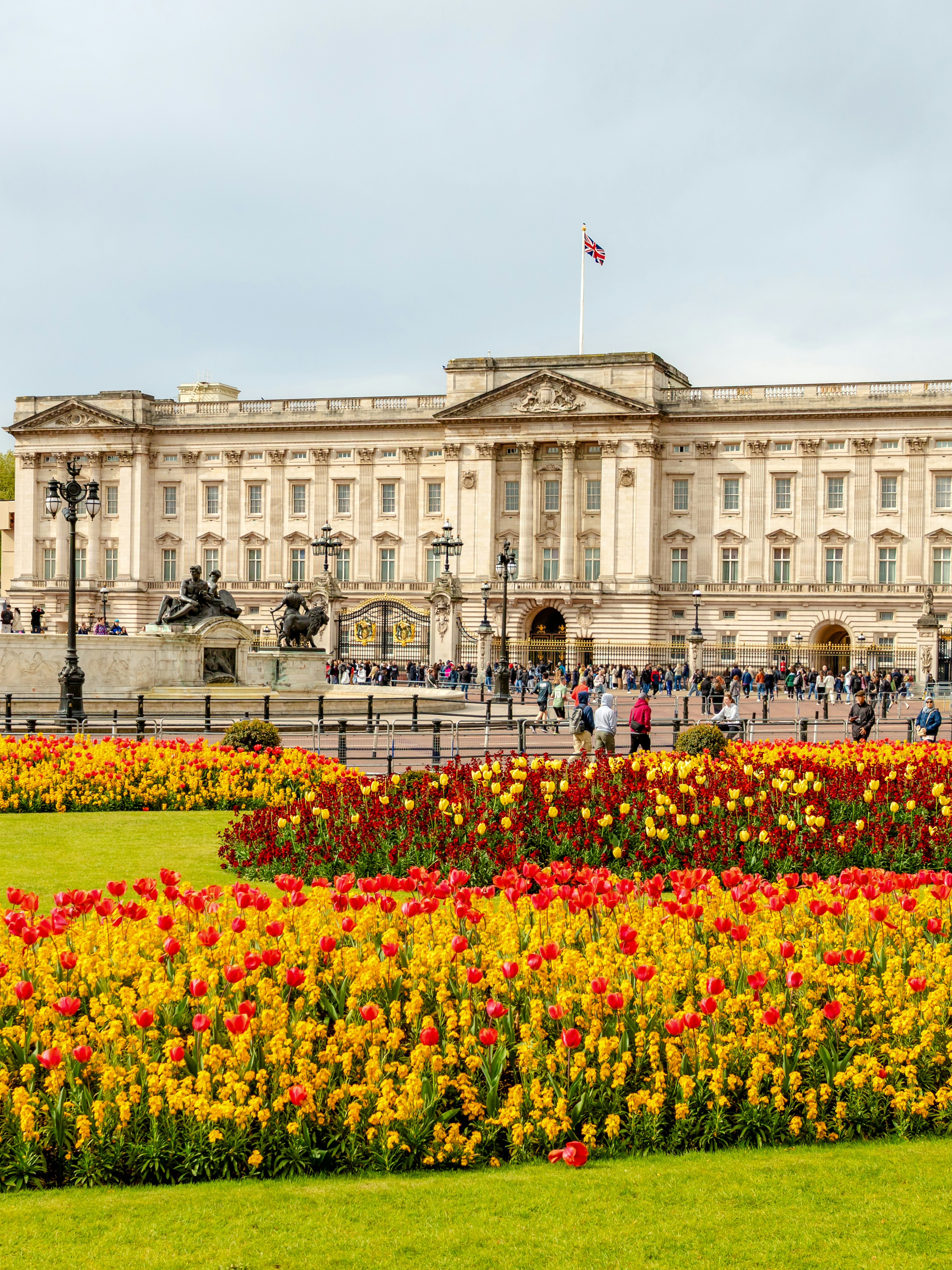 Buckingham Palace with Victoria Memorial and colorful flower gardens in London.