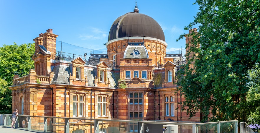 Royal Observatory Greenwich with brick architecture and dome under clear sky.