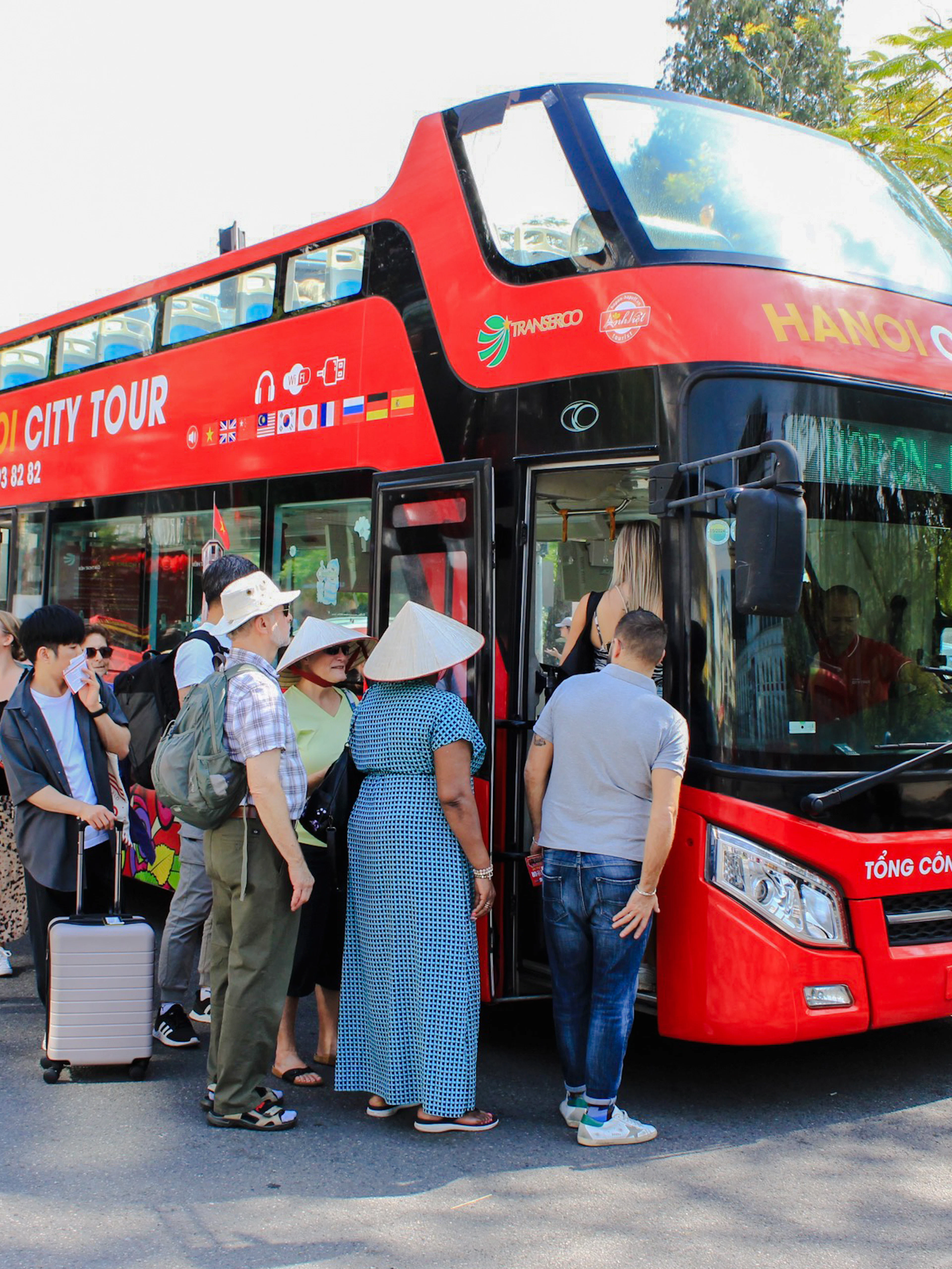 Tourists boarding a red hop-on hop-off bus in Hanoi, Vietnam.