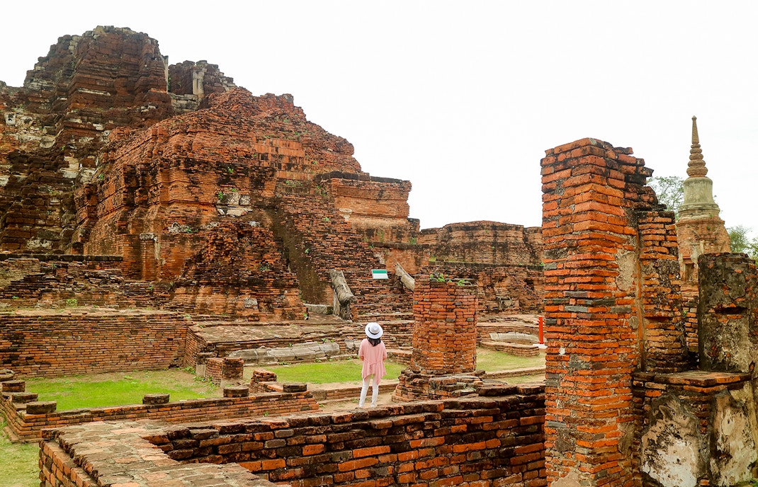 Visitor exploring ancient ruins at Ayutthaya Historical Park, Thailand.