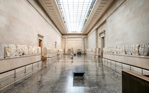 British Museum gallery with ancient sculptures on display during guided tour.