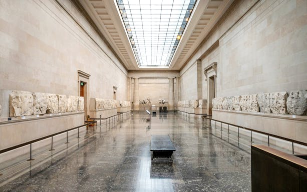 British Museum gallery with ancient sculptures on display during guided tour.