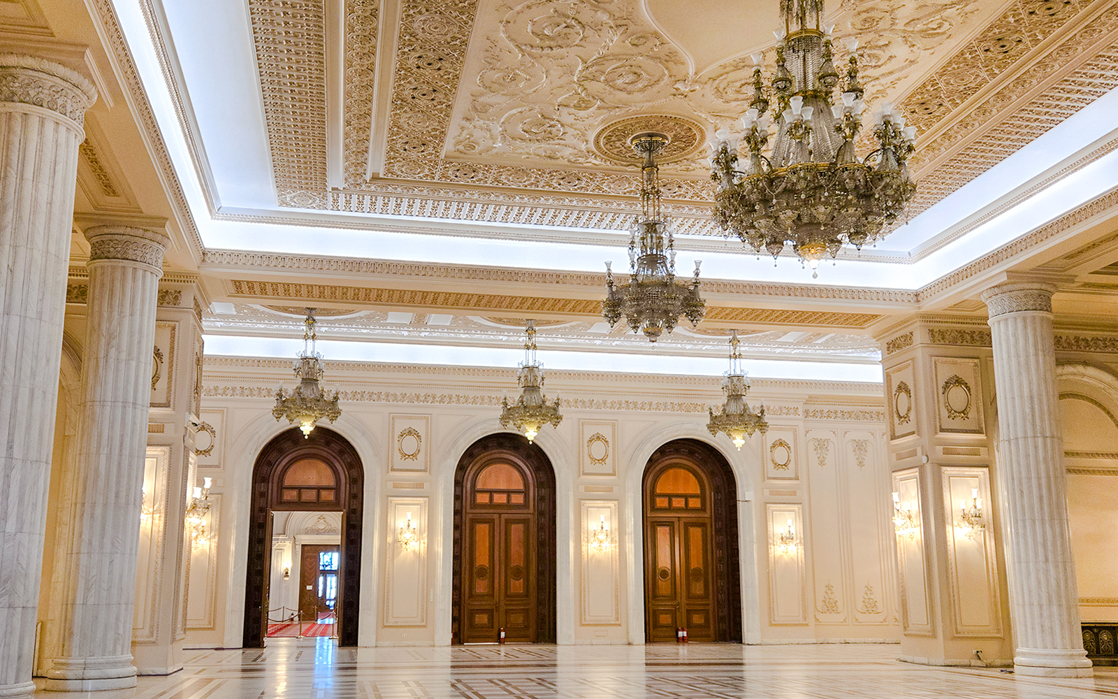 Palace of Parliament interior with ornate chandeliers and marble columns.