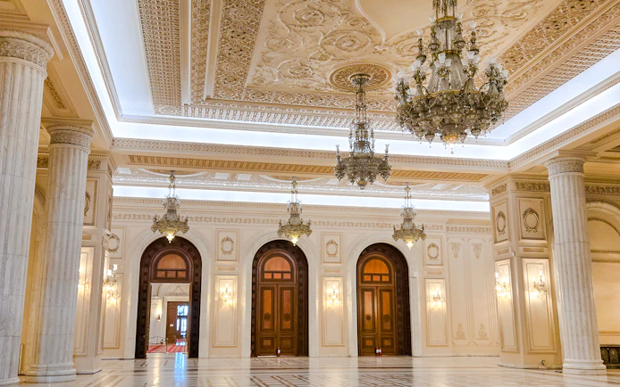 Palace of Parliament interior with ornate chandeliers and marble columns.