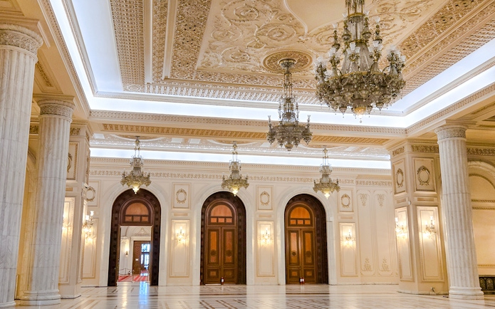 Palace of Parliament interior with ornate chandeliers and marble columns.