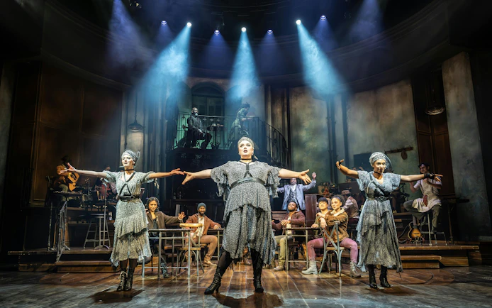 Stage performance of Hadestown in West End with actors in dramatic pose.
